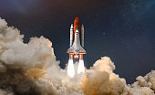 Space shuttle in sky with stars and clouds. Rocket in deep space sci-fi concept. Astronauts and spaceship. Elements of this image furnished by NASA