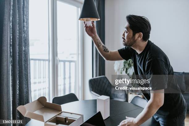 hombre instalando bombilla inteligente - eficiencia energetica fotografías e imágenes de stock