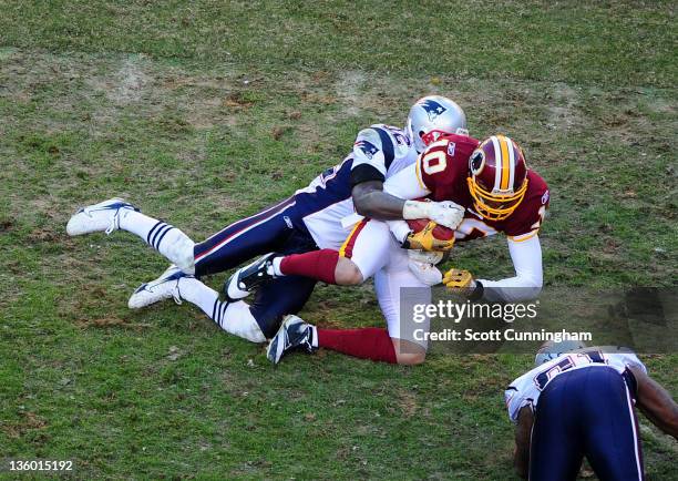 Jabar Gaffney of the Washington Redskins is tackled by Devin McCourty of the New England Patriots at FedEx Field on December 11, 2011 in Landover,...