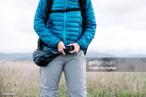 unrecognizable person buckling his backpack around his waist in the middle of a hill. - schnalle stock-fotos und bilder