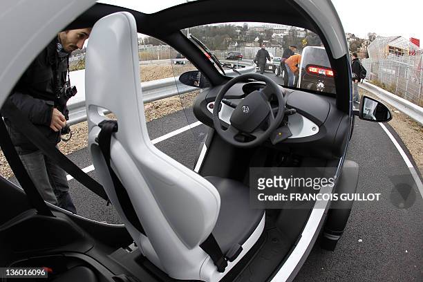 Man looks at a new Renault electric car Twizy Z.E, on a test track, on December 20, 2011 at the Ile Séguin test centre for electric vehicles in...