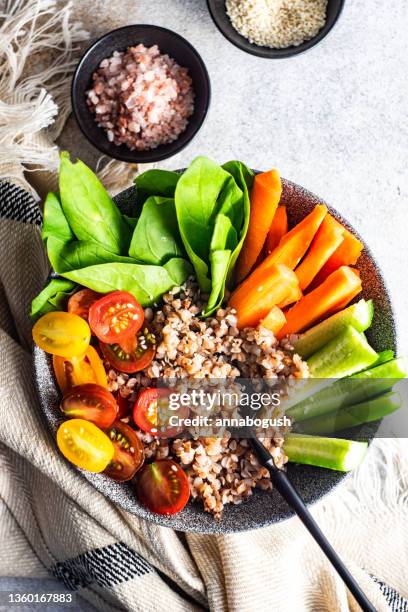 overhead view of a buddha bowl with buckwheat, lettuce, carrot, tomato and cucumber - buddha bowl stock pictures, royalty-free photos & images