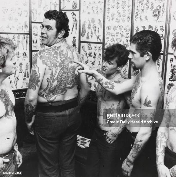 Friends admire Big John Quantick's tattoos. 24th October 1965. It’s the latest craze! All eyes on Big John Quanticks as his friends admire his...