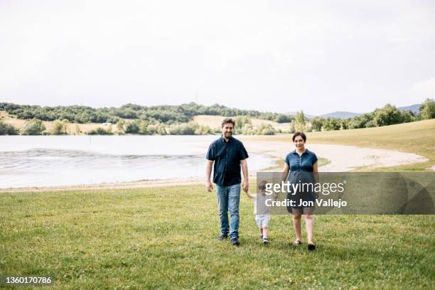 a loving family of a son holding hands in the park walking forward - walking forward stock-fotos und bilder