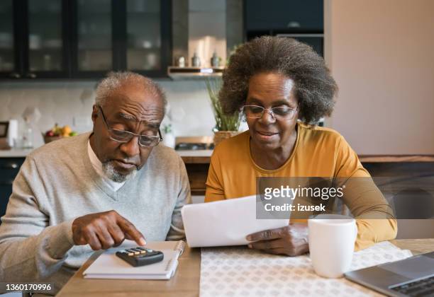 senior couple going through bills - senior couple laptop stock pictures, royalty-free photos & images