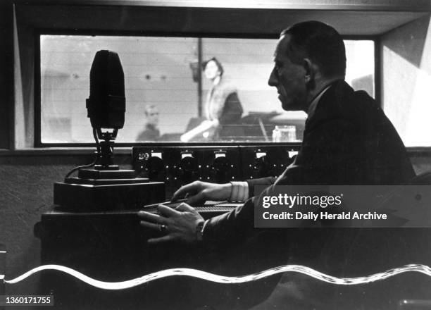 Listening to an audition in Broadcasting House, London, 10 March 1936. A BBC member of staff in a studio with microphone and radio sound equipment.