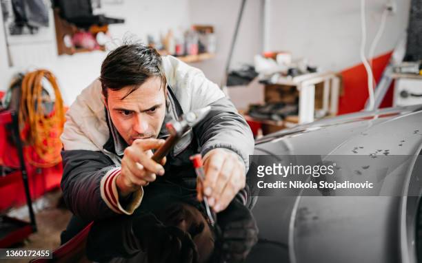 technician using protective gloves is in process of paintless dent repair on car - dented stock pictures, royalty-free photos & images