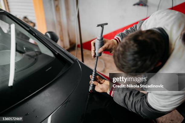 technician using protective gloves is in process of paintless dent repair on car - car deuk stockfoto's en -beelden