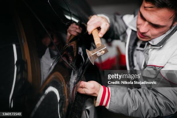 hombre arreglando la abolladura del coche por sí mismo - abollado fotografías e imágenes de stock