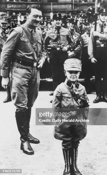 Adolf Hitler with a young boy wearing the uniform of the SA . A photograph of Adolf Hitler with a young boy wearing the uniform of the SA .