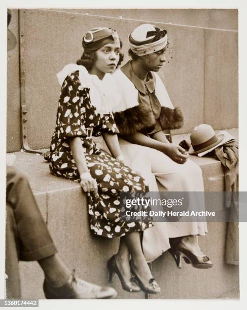 Photograph of two women in stylish dress seated at a demonstration against the Italo-Abyssinian war in Trafalgar Square, London. A photograph of two...