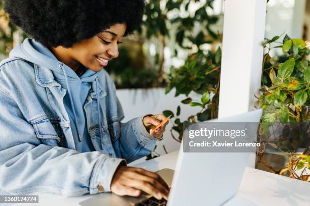 afro woman holding a credit card and using laptop computer while - customer experience stock pictures, royalty-free photos & images