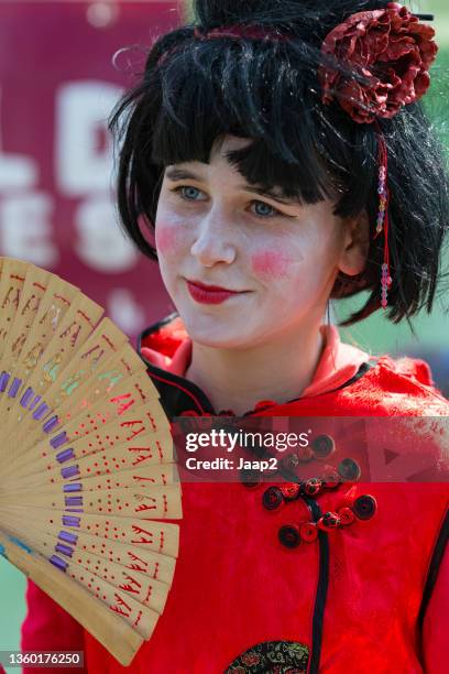 living statue performer posing as a young chinese woman - levend standbeeld stockfoto's en -beelden