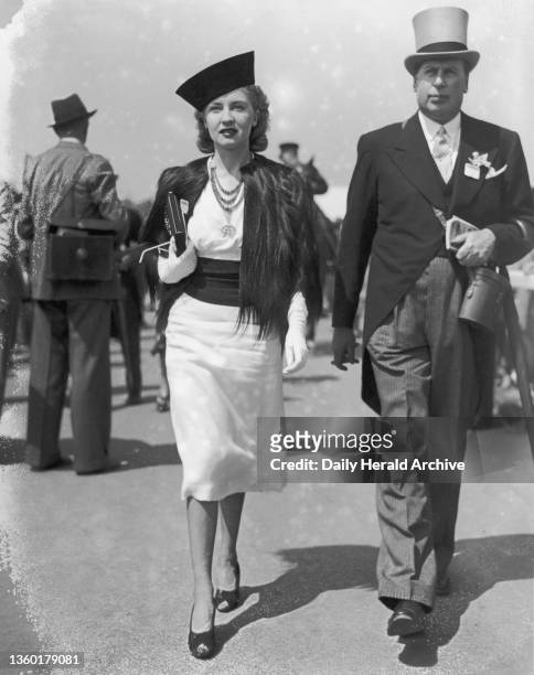 Fashions at the Royal Ascot Races, 14 June 1938. A couple promenading at the races wearing the fashions of the day, she wears a small hat worn...