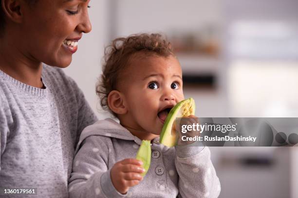 mom feeds baby avocado. - baby eating stock pictures, royalty-free photos & images