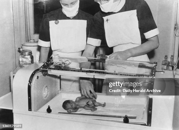 Nurses with a tiny baby in his incubator. Four nurses watch on Britain's smallest baby: five days old - weighs 25 ounces. Britain's smallest baby -...