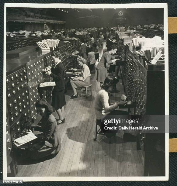 Employees searching for names held in a card index system. Gelatin silver photograph. FBI employees searching for names held in a card index system...