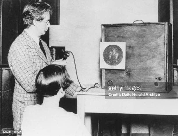 John Logie Baird conducting a demonstration of his receiving station, circa 1927. 'The round screen on the front of the cabinet shows an assistant...