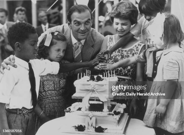 Mandy Miller assisted by some of her guests cuts her birthday cake at a party she gave to 100 orphans at the Battersea Fun Fair. Shown here with...