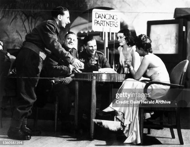 Soldiers and women around ballroom table, 1939. 'In the interval at this theatre a Tommy can do what he even can't do in Paris. He can go down to the...