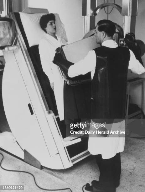 Woman being x-rayed by the Marconi large screen image amplifier - a new type of x- ray equipment - will lead to a considerable lessening of the x-ray...