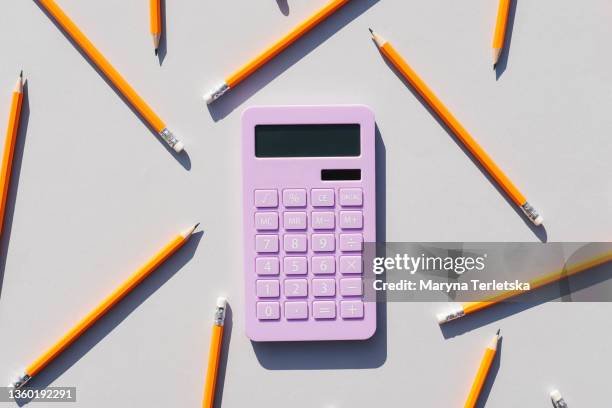 calculator and non-colored pencils on a gray background. universal gray background. calculator. educational supplies. - price calculator stock-fotos und bilder