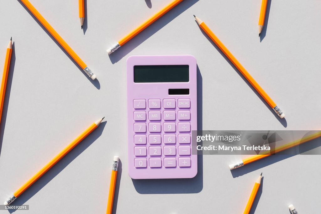 Calculator and non-colored pencils on a gray background. Universal gray background. Calculator. Educational supplies.
