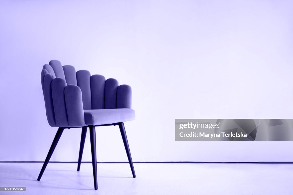 Purple textured velor armchair on a purple background. Armchair in the form of a shell. Design. Purple background. Fashionable color Very Peri. Universal background.