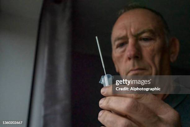 a senior man doing a lateral flow test for covid-19 - antibody testing imagens e fotografias de stock