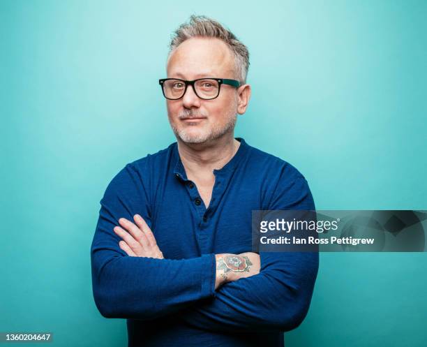 tattooed hipster with arms crossed - man blue background stockfoto's en -beelden