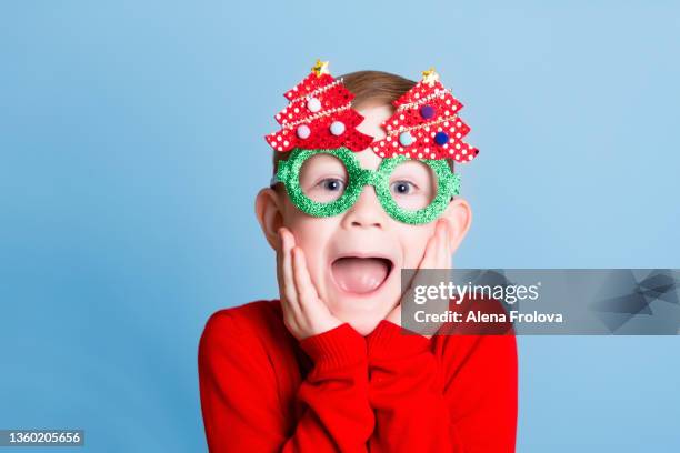 portrait of beautiful cute boy dressing christmas eyeglasses on blue background - kids dressing up stock-fotos und bilder