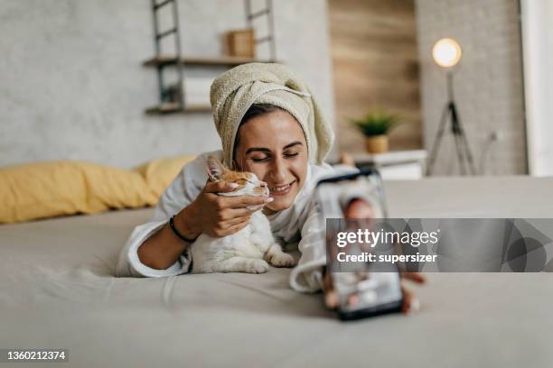 young woman in towel relaxing with cat - cat selfie stock pictures, royalty-free photos & images