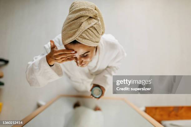 young woman in towel relaxing after shower - cream for face stock pictures, royalty-free photos & images