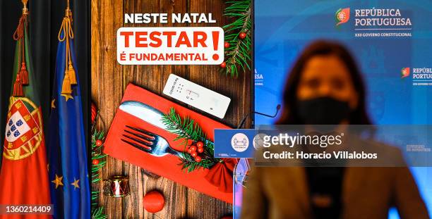 Reporter wears a protective mask as she stands in front of an electronic billboard stating "It is fundamental to test on Christmas" while waiting for...