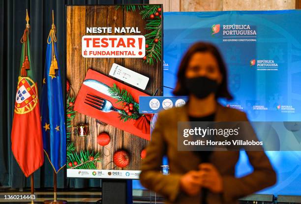 Reporter wears a protective mask as she stands in front of an electronic billboard stating "It is fundamental to test on Christmas" while waiting for...