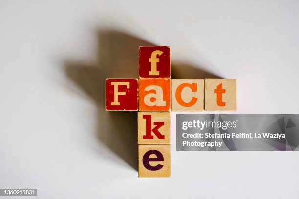 fake  fact concepts with wooden text alphabet block on white surface - liar stock pictures, royalty-free photos & images