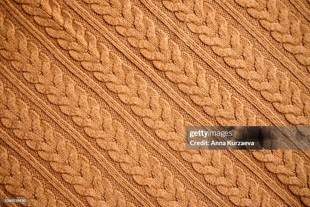 Texture of warm knitted sweater. Backdrop in brown color.