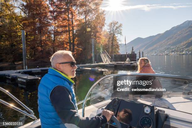 young man and mature man on luxury boat, they enjoy the lake in autumn - motorboot stockfoto's en -beelden