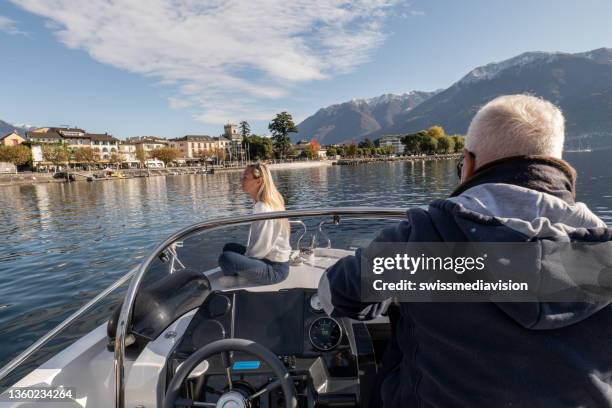 junger mann und reifer mann auf luxusboot, sie genießen den see im herbst - lago maggiore stock-fotos und bilder