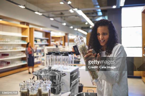 woman shopping for pepper grinder in home goods store - caiaimage stock-fotos und bilder