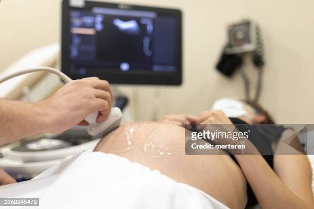 junge schwangere frau, die ihr baby beim arzt im ultraschall untersuchen lässt - baby in womb stock-fotos und bilder