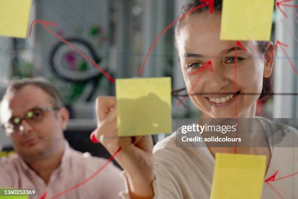 session de brainstorming dans un bureau modern - réfléchir écrire adulte 40 ans papiers photos et images de collection