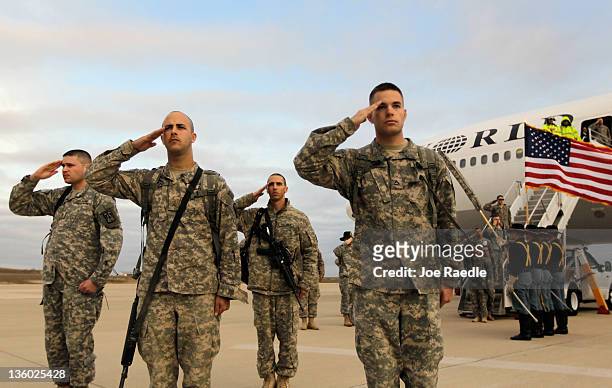 Army soldiers from the 2-82 Field Artillery, 3rd Brigade, 1st Cavalry Division, salute after walking off the plane as they arrive at their home base...