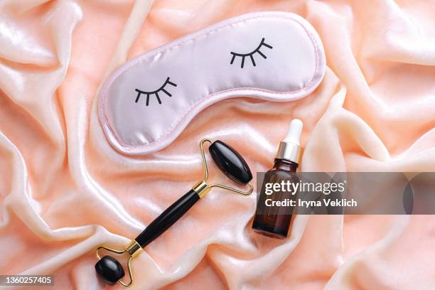 nigth  preparation concept with sleep eye mask  and beauty products on delicate pink peach color velvet or silk background. - máscara de olhos imagens e fotografias de stock