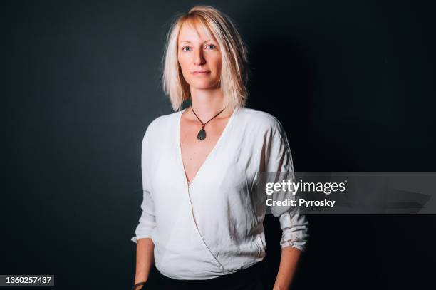 young woman with hands in pockets isolated on dark background - portrait professional dark background stock pictures, royalty-free photos & images