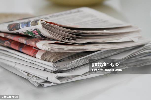 a pile of newspapers on table - newspaper stack stock-fotos und bilder