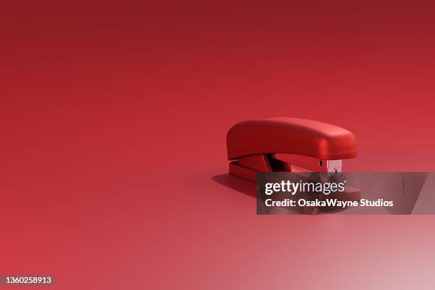 red manual office stapler on red background - staples office stockfoto's en -beelden