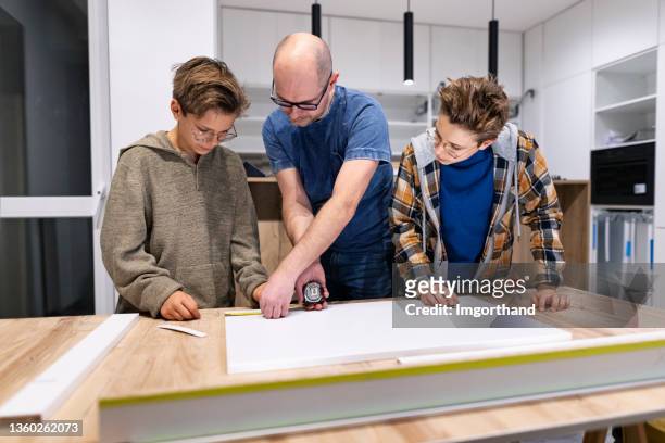 father and sons making kitchen installation at home - wood accuracy stock pictures, royalty-free photos & images