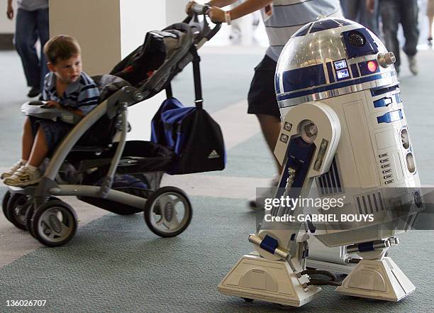 Star Wars character R2-D2 is closely observed by a child in a stroller during the opening day of "Star Wars Celebration IV" in Los Angeles, 24 May...