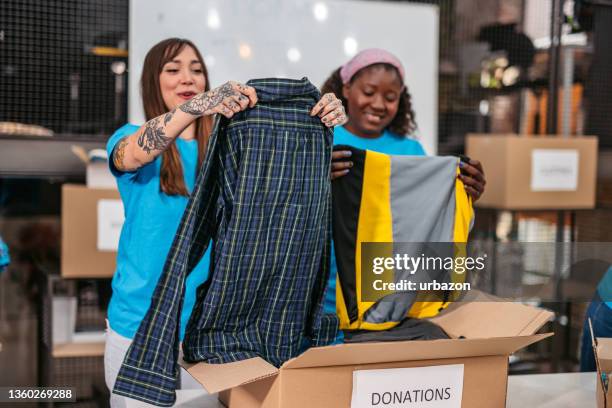 volunteers in donation center folding and packing clothes in boxes - filantropista imagens e fotografias de stock